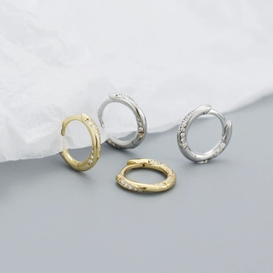 Detail view of twisted S925 silver hoop earrings with cubic zirconia in gold and silver