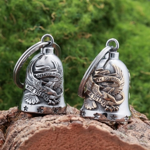 Close-up of stainless steel eagle guardian bells with Live to Ride engraving on mossy wood