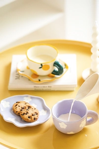 Top view of ceramic coffee cup sets with lemon and floral patterns on a yellow table