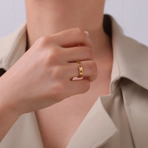 Gold stainless steel ring with animal paw print cutouts worn on a model's finger