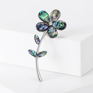 Macro shot of an iridescent abalone shell flower brooch with silver stem and crystal