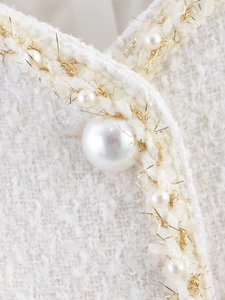 Dettaglio di giacca in tweed bianco con bottoni di perle e dettagli in filo d'oro