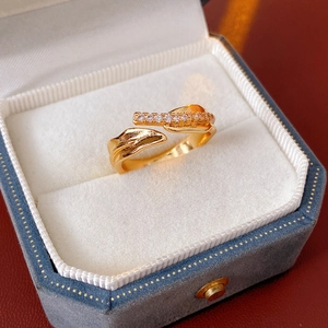Détail d'une bague dorée en forme de feuille avec zircon blanc dans un écrin bleu