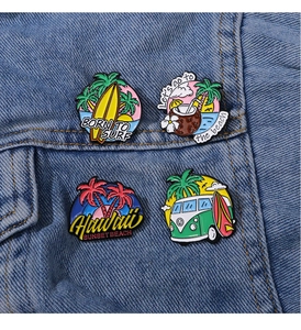 Detail of tropical enamel pins with beach motifs pinned on a blue denim jacket