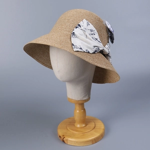 Detail of woven straw sun hat featuring a blue floral bow and tight texture on wide brim