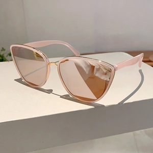 Detailed macro view of pink cat-eye sunglasses with gold metal frame on white pedestal