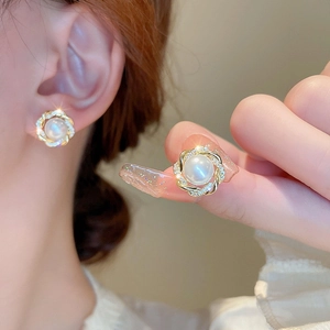 Detailed view of pearl earrings with gold twisted frame and sparkling rhinestones