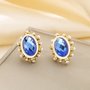 Detail of oval blue crystal earrings with gold base and small white pearl trim