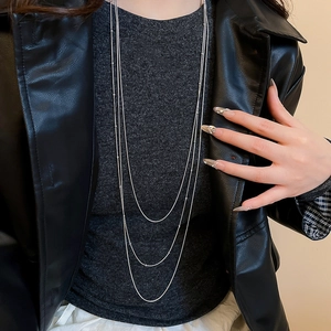 Close-up of triple-layered silver tassel necklace featuring delicate beads on a model