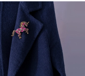 Retro golden unicorn brooch with pink crystals pinned on a dark blue wool jacket lapel