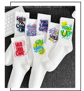 Close-up of white cotton athletic socks featuring motivational text embroidery on dark background