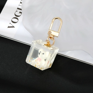 Detail of white resin bear inside clear cube pendant with glitter and gold D-ring hook