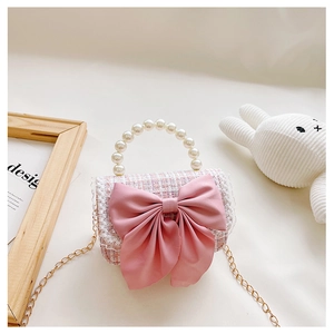 Detail of tweed girl's handbag with large pink satin bow and pearl handle