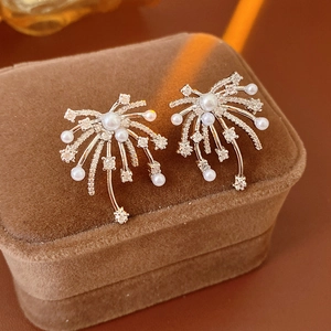 Macro detail of firework pearl earrings with sparkling zircon on brown velvet gift box
