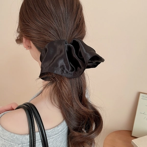Close-up of black satin oversized scrunchie worn on a ponytail for a French chic look
