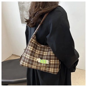 Close-up of brown checkered shoulder bag featuring detailed dachshund dog embroidery