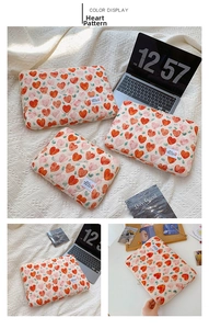 Detail of quilted laptop sleeve featuring vibrant red heart patterns and white lucky label