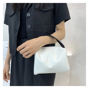 Chic white cloud handbag with contrast black handle worn by model in minimalist setting