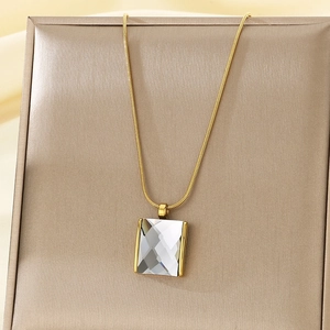 Detail of gold snake chain with square faceted glass pendant on jewelry display