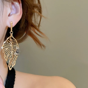 Detail of gold leaf drop earring with delicate black and white butterfly ornament
