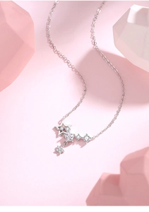 Macro detail of 925 sterling silver star necklace with zircons on pink background