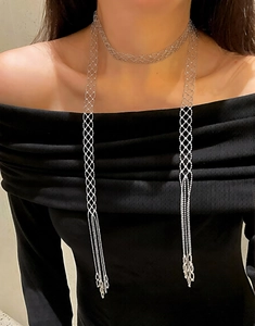 Detailed view of silver crystal mesh body chain with long tassels on a model