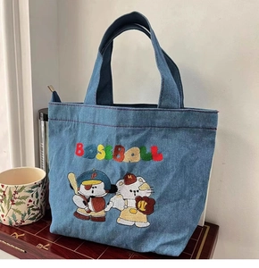Detail shot of a blue denim tote bag featuring colorful cartoon baseball embroidery