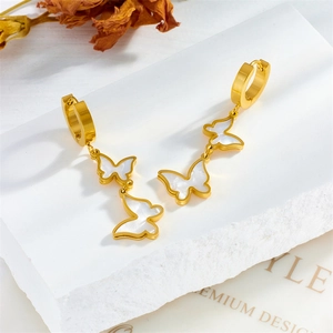 Gold-plated stainless steel butterfly drop earrings with white shell inlay on marble