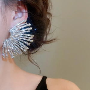 Macro view of fan-shaped silver earrings with sparkling crystals worn by a model