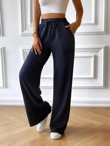 Detail of high-waisted navy blue wide-leg trousers with drawstring and ribbed texture