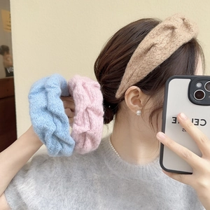 Close-up of thick knitted headband and fluffy scrunchie in light blue and soft pink colors