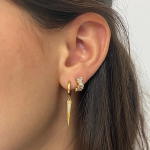 Detail view of gold hoop earrings with baguette cut zircons and a spike pendant