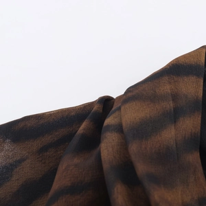 Détail de la texture du tissu imprimé animal noir et marron avec matière de robe midi