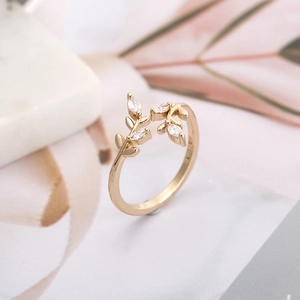 Elegant gold leaf ring with sparkling zircons on a white marble and pink leaf backdrop
