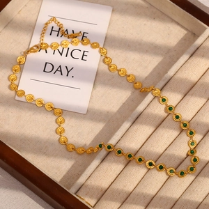 Retro 18K gold plated necklace with green stone discs on a beige jewelry display tray