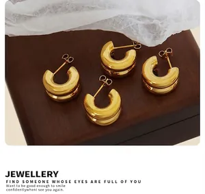 Détail de boucles d'oreilles doubles en C dorées sur bois avec touches de tissu doux