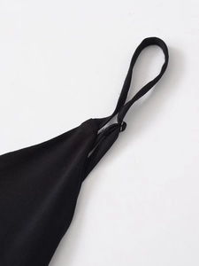 Close-up of black crepe dress showing adjustable spaghetti strap and fine stitching