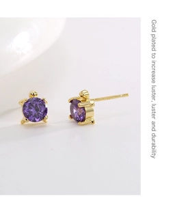 Macro detail of gold plated turtle stud earrings featuring round purple zircon stones