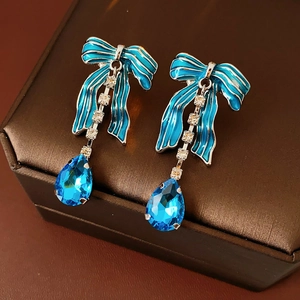 Dettaglio macro degli orecchini a fiocco blu con frange di strass e gemma a goccia