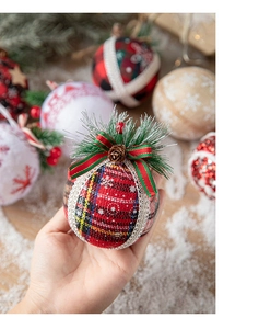 Close-up of red and green plaid Christmas ball with pine needles and cones detail