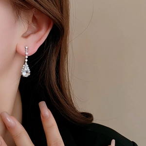 Close-up of silver water drop tassel earrings with sparkling rhinestones on model