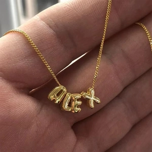 Close-up of golden stainless steel 3D balloon pendant necklace spelling ALEX