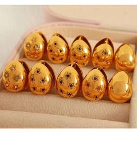 Nahaufnahme goldener Tropfenohrringe mit bunten Sternkristallen in einer Box