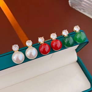 Vue détaillée de boucles d'oreilles perles et zircons en blanc, rouge et vert