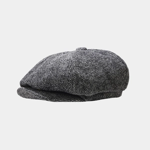 Detail of herringbone tweed newsboy cap showing texture and fabric stitching