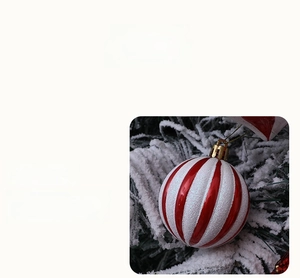 Detail of red and white striped glitter Christmas ball hanging on a snowy tree branch