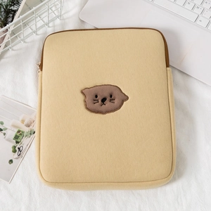 Close-up of yellow velvet laptop sleeve featuring brown beaver embroidery on a white table