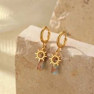 Detail of golden sun pendant earrings with rectangular colorful stone on stone background