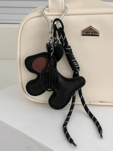 Detail of dog-shaped leather charm with mini tennis racket on white leather bag