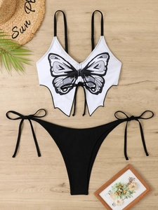 Flat lay of butterfly print two-piece bikini set with straw hat on wooden background